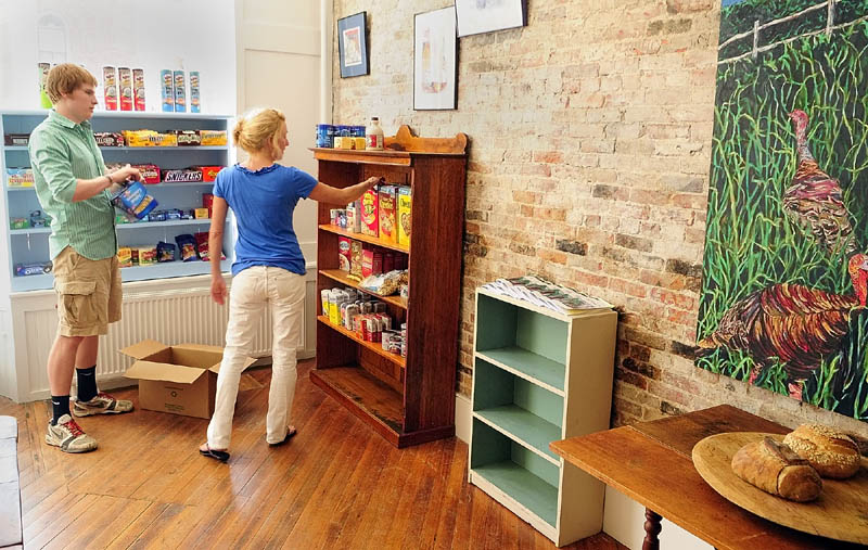 Sam Estes, left, and Jeanne Langsdorf stock shelves on Friday morning at the newly opened store called The Market on Water Street in Hallowell. The store is located in a former antique store next to where Boynton's Market used to be.