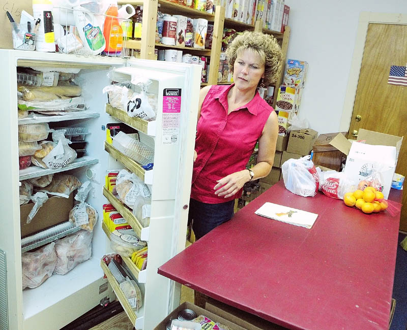 BARELY ROOM TO MOVE: Volunteer Diane Dow demonstrates how the refrigerator door can’t open in the 12-by-15 foot room where the food bank operates in the Windsor Town Office. The Windsor Food Bank is trying to raise funds to move into larger quarters. The town is not contributing any taxpayer money, Board of Selectmen Chari Ray Bates said, but Windsor is providing the space: A 16-by-34 foot garage bay, one of three in the town garage next door.