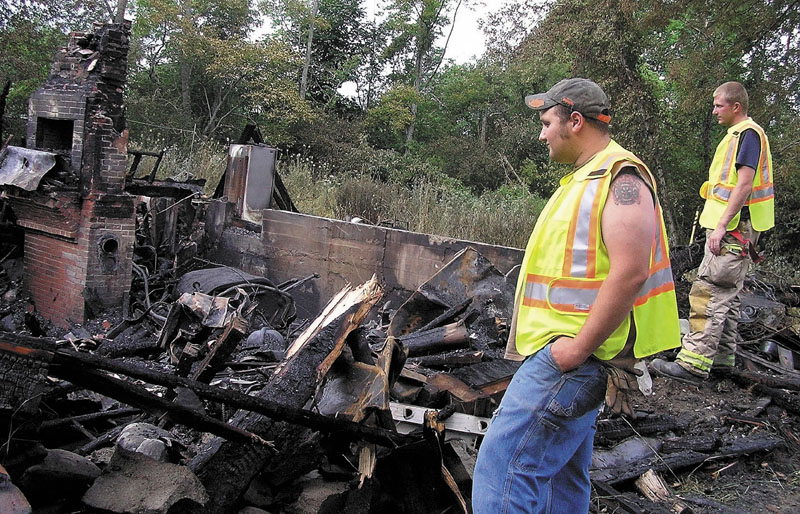 PILE OF RUBBLE: Clinton firefighters Andrew Gerow, left, and Anthony Barton survey the damage Tuesday morning after a fast-moving fire destroyed a house on Battle Ridge Road in Clinton.