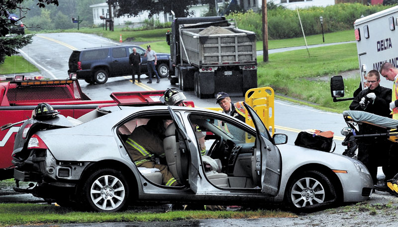 CLOSE CALL: Rescue workers remove David Brophy, who was injured Tuesday after his car and a loaded dumptruck, background, collided on Clinton Avenue in Winslow.