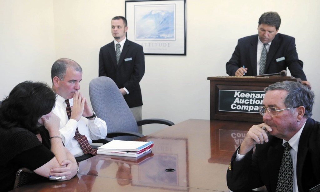 AUCTION: Camden National Corporation senior vice president Stephen Matteo, second from left, waits Monday for Keenan Auction Company employees, right, to close the bidding for the former Associated Grocers of Maine buildings in Gardiner during an auction for AG’s real estate. Camden National Corporation, which held a bank note on the property, made the highest bid.