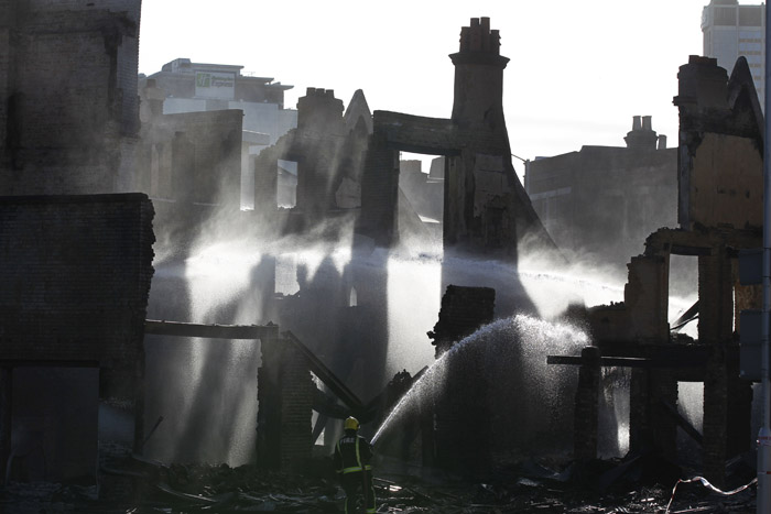 A firefighter today sprays water on a furniture store set on fire by rioters Monday night in Croydon, south London.