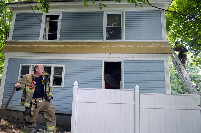 BEAT THE HEAT: Augusta firefighter Greg Coniff, left, catches his breath Tuesday as a colleague ascends a ladder into an Augusta home that caught fire. Firefighters were able to extinguish the blaze quickly.