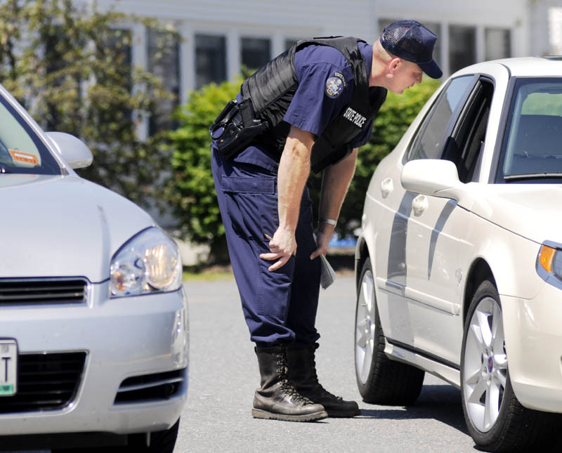 Maine State Police Detective Adam Kelley speaks to the driver of a car Monday in the parking lot of the Manchester Elementary School following the robbery of a Rite Aid store next door in Manchester. Police were searching for a man who held up the store on Route 202 at 11 a.m.