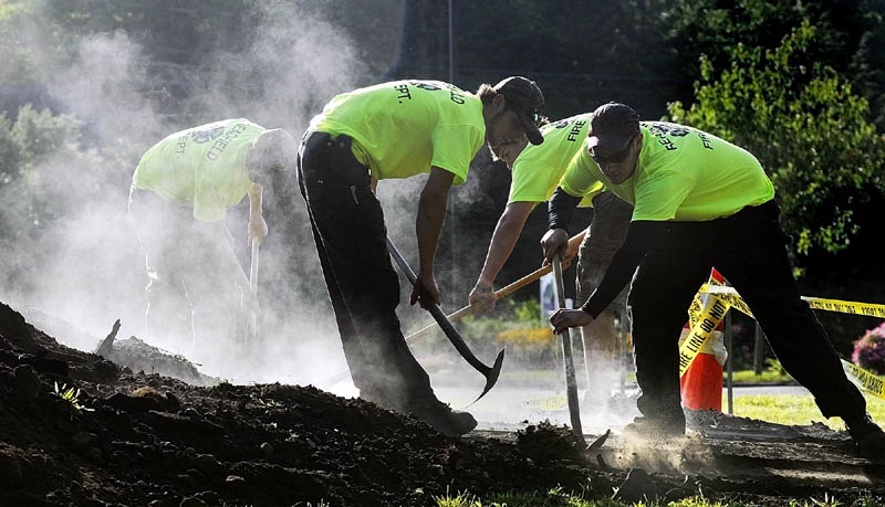 Readfield firefighters shovel dirt of the top of the steel plates covering their beanhole beans on Saturday morning during Readfield Heritage Days. The previous evening firefighters dug a large hole and started a cook fire with about a cord of firewood. When it had burned down to coals they lowered three large custom made steel bean pots each with 25 pounds of beans and a "secret recipe" of other ingredients into the hole. They were to be served Saturday evening.