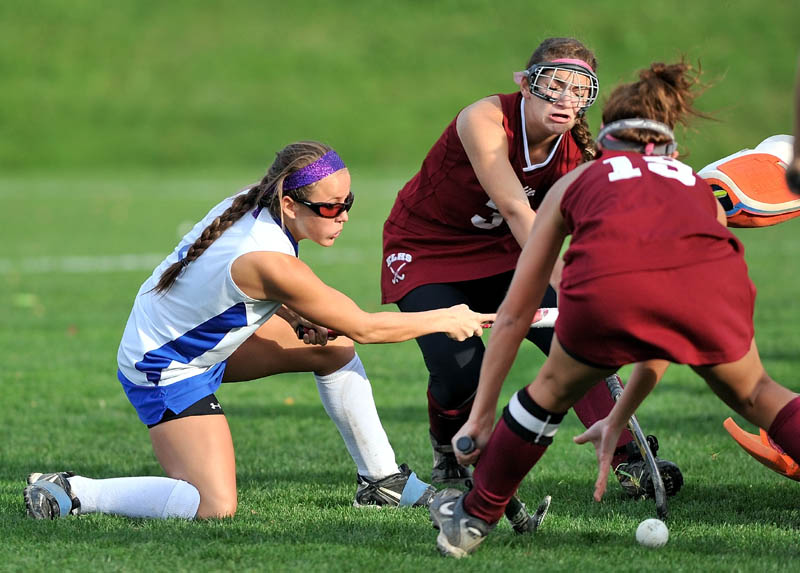 Staff photo by Michael G. Seamans Lawrence High School's Danielle Armour, 4, left, takes a shot on goal btween Edward Little High School defenders Kaelina Perron, 3, center facing, and Kayla Nadeau, 19, right, in the second half of the Eastern A quarter fianls game at Lawrence High School in Fairfield Tuesday. Lawrence defeated Edward Little 2-0.