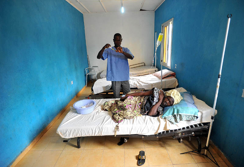 A healthcare worker at a rural healthcare clinic operated by the WellBody Alliance treats a woman suffering from malaria. The Wellbody Alliance has been providing community-based healthcare to the Kono District in Sierra Leone. New legislation has been passed by the Sierra Leone government that provides free healthcare to pregnant and lactating women and children under the age of five in an effort to address the highest infant and maternal mortality rates in the world.