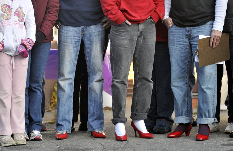WAITING TO WALK: Three men in red high heels wait for the Walk a Mile in Her Shoes event in Skowhegan Saturday morning.