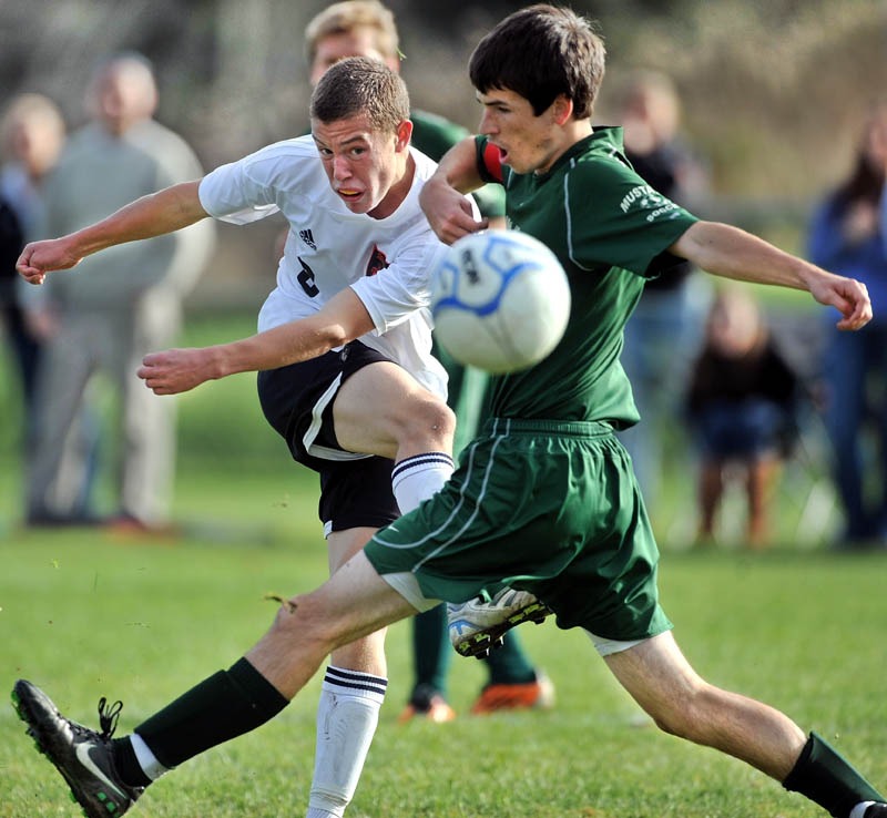 Staff photo by Michael G. Seamans Winslow High School's Gabe Smith, 8, shoots through Mt. View High School defender Adam Higgins, 8, in an Eastern B quarterfinal game at Kennebec Savings Bank Field in Winslow. Mt. View won 3-0.