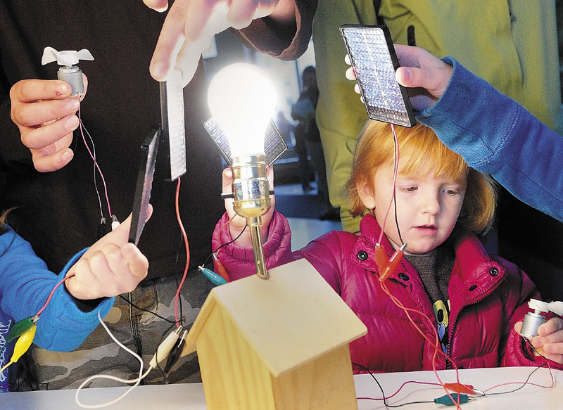 HANDS-ON LEARNING: Ruby Dufour, 3 of Winthrop, holds a photovoltaic cell to a light bulb that powers the spinning fan in her other hand Wednesday morning at the Maine Energy Education booth during the Earth Science Day at the Maine State Museum in Augusta. About 1,000 visitors checked out the 15 displays, such as gold panning and exploring how to quarry granite.