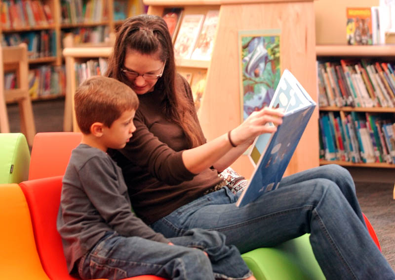 READ ALL ABOUT IT: Christine Hufnagel reads to her son, Connor, in the library of the new W.G. Mallet School in Farmington Saturday morning. Connor, 6, a first-grader at the school, said he liked the new school and “the library is huge!”