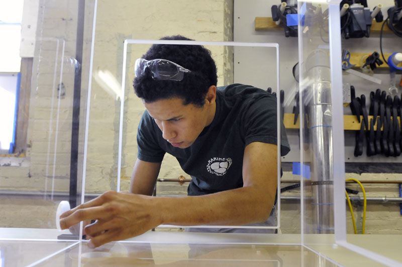 CUSTOM FIT: Matthew Laforest dry fits a base tank at Marine Ecological Habitats in Biddeford last month. The company has been making custom-built aquariums and tanks for 10 years