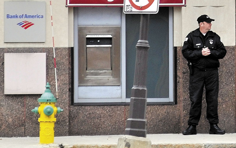WATCHING: A private security guard stands outside the Bank of America on Main Street in downtown Waterville on Thursday.