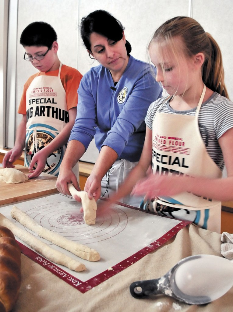 KNEAD THIS WAY: Gina Ciancia, center, an instructor with the King Arthur Flour company, works with Messalonskee Middle School students Parker Poulin and Madyson Foster while making bread on Tuesday. Students were giving instructions and materials to bake bread and donate to area food cupboards.