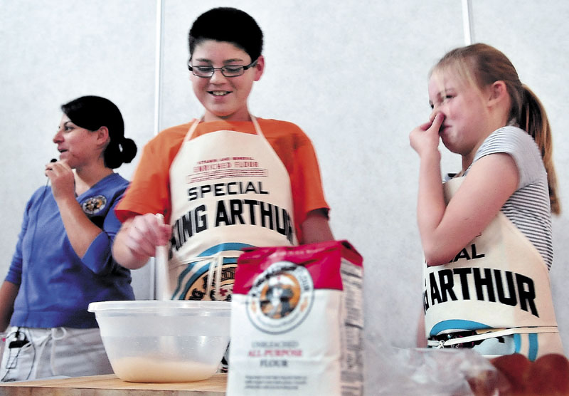 BREAD DREAD: Messalonskee Middle school student Madyson Foster holds her nose at the smell of yeast and flour being mixed by Parker Poulin on Tuesday as Gina Ciancia of the King Arthur Flour Company teaches students to bake bread.