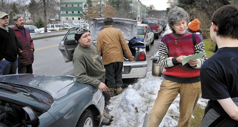 A PERMIT TO ASSEMBLE: Occupy Augusta movement member Diane Messer, second from right, inspects a permit Monday she was directed to fill out by Capitol Police for an application to protest in Capitol Park in Augusta. The group requested a restraining order in U.S. District Court to impede the State of Maine from enforcing the permit, according to Messer.