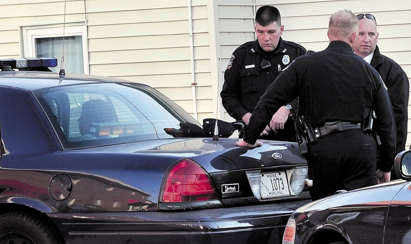 SUSPECT: A male suspect sits in a cruiser at the Big Apple on Elm Street as Waterville police officers Galen Estes, left, Tim Hinton and Detective Sgt. Michael Beneche investigate a robbery at the Bank of America on Monday.