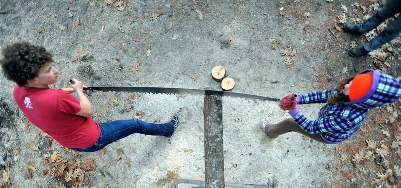 BACK AND FORTH: Colby College sophomore Liz Schell, left, introduces Morgaine Kmen, 10, to the cross-cut saw as part of the Adventure Girls Series on Saturday afternoon in Waterville. Adventure Girls meets once a month with women who are defying gender stereotypes and challenging notions of what a girl or woman should be doing with her life. The group learns about backpacking, compass reading and outdoor orienteering and meet women firefighters, welders, carpenters, farmers, engineers, police officers and pilots.