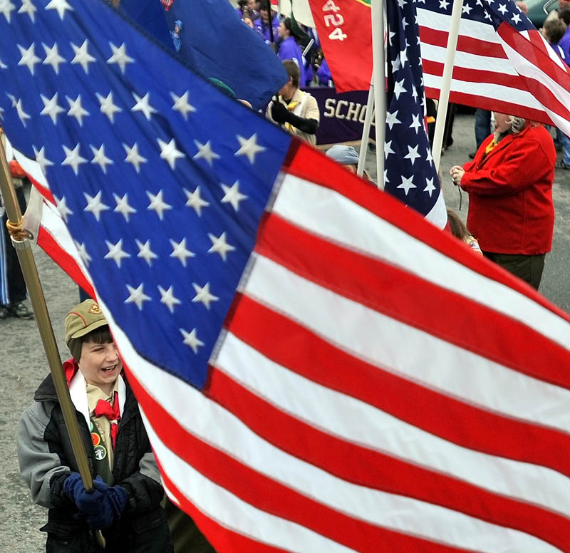 READY TO CELEBRATE: Matrim Glazier, 12, bottom left, with Boy Scout Troop 436, stands with an American flag at Head of Falls before the Veterans Day parade Friday in Waterville.