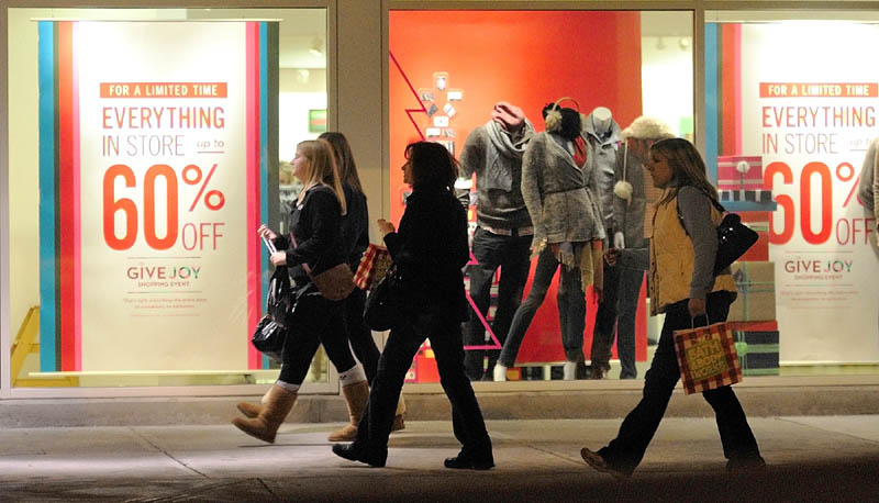 Shoppers walk in front of a window display in The Marketplace at 4:35 a.m. Friday in Augusta. Shopping centers were crowded overnight as retailers were offering big discounts. Some stores opened as early as 12:01 a.m.