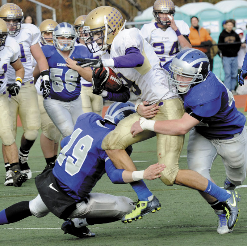 ON THE MOVE: Cheverus receiver Louie DiStasio runs is hit by Lawrence defenders Alex Leathers, left, and Luke Lawrence, right, during the Class A state championship game Saturday at Fitzpatrick Stadium in Portland. DiStasio caught four passes for 130 yards in the Stags’ 49-7 win over Lawrence.