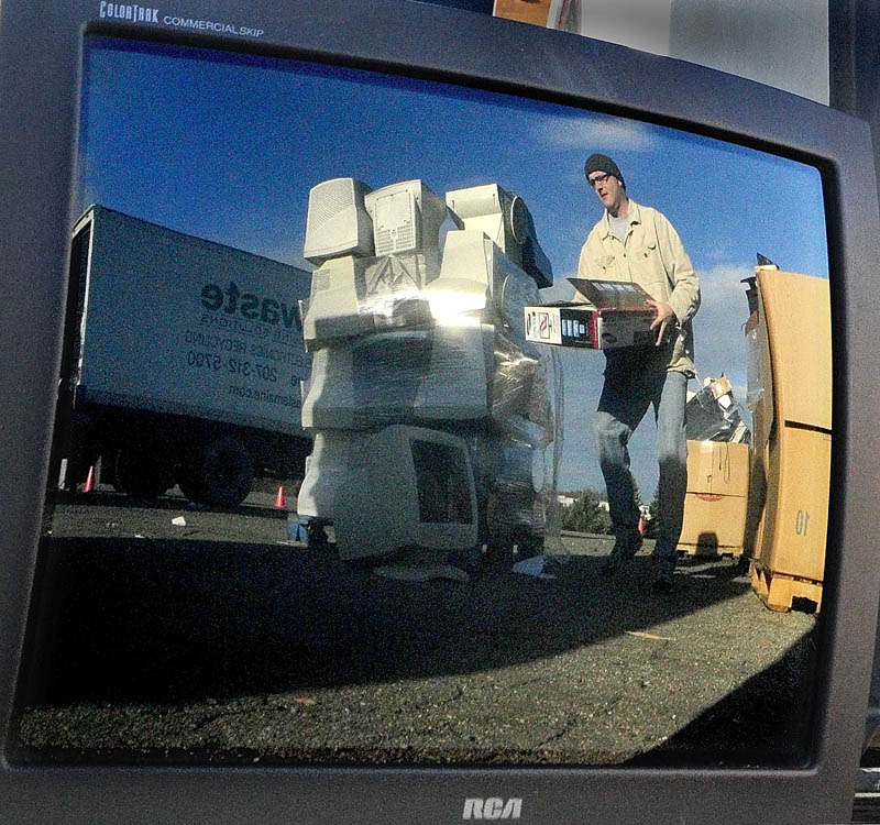 Jon Martin is reflected in an old television as he piles up old electronics during recycling event on Saturday at the Augusta Civic Center.