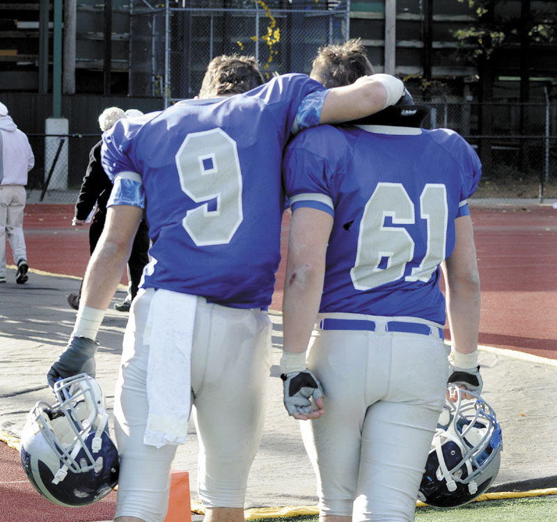WALKING AWAY: Lawrence’s Spencer Carey (9) and Josh Perry walk off the field after the Bulldogs lost to Cheverus 49-7 in the Class A state championship game Saturday at Fitzpatrick Stadium in Portland.