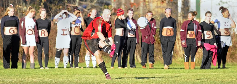 SHOW OF SUPPORT: Richmond goalkeeper Tyler Harrington kicks the ball during the Western Maine Class D championship game Wednesday in Richmond as members of the Bobcats girls team, who painted their stomachs for the occasion, cheer on the boys after winning their playoff game.