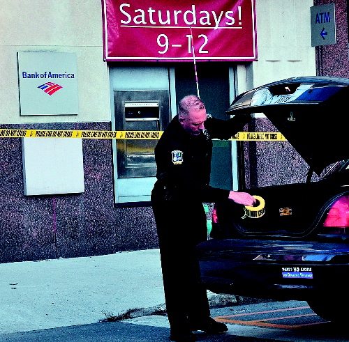 Waterville police officer Tim Hinton finishes taping off the front and rear of the Bank of America on Main Street in Waterville after a male entered the bank on Monday with a suspicious bag and left with an undetermined amount of money. The man was arrested nearby on suspicion of robbery.