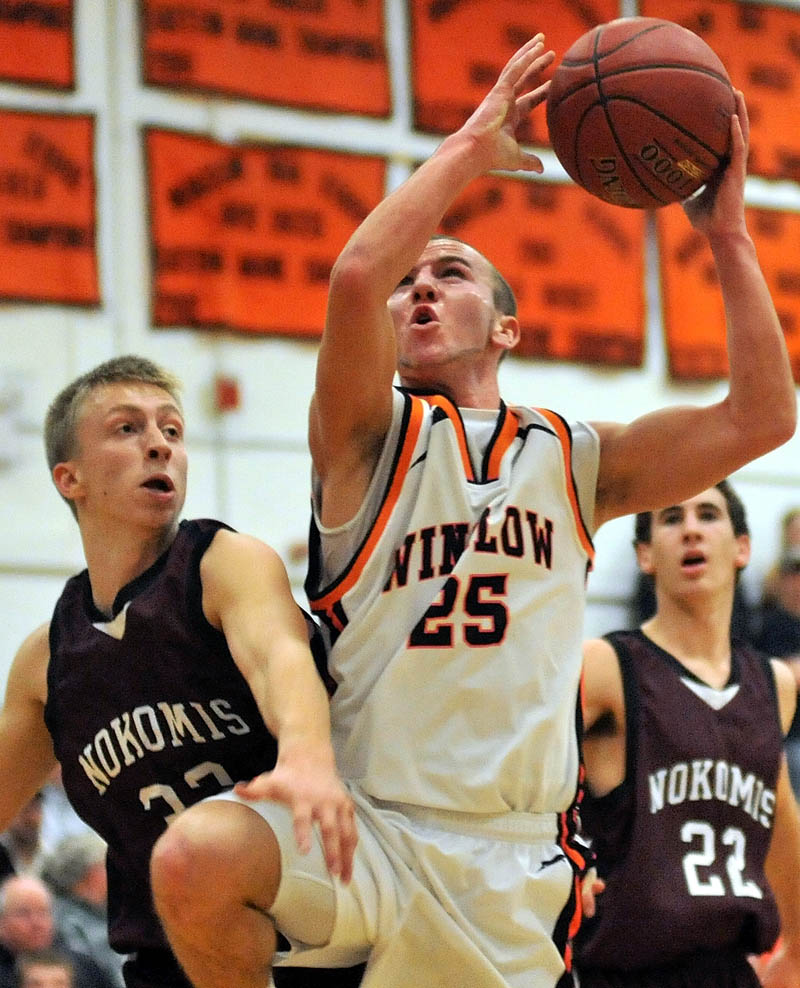 Winslow High School's Justin Murry, center, draws a foul from Nokomis Regional High School's Drew Wing, left, during the first quarter Friday night in Winslow.