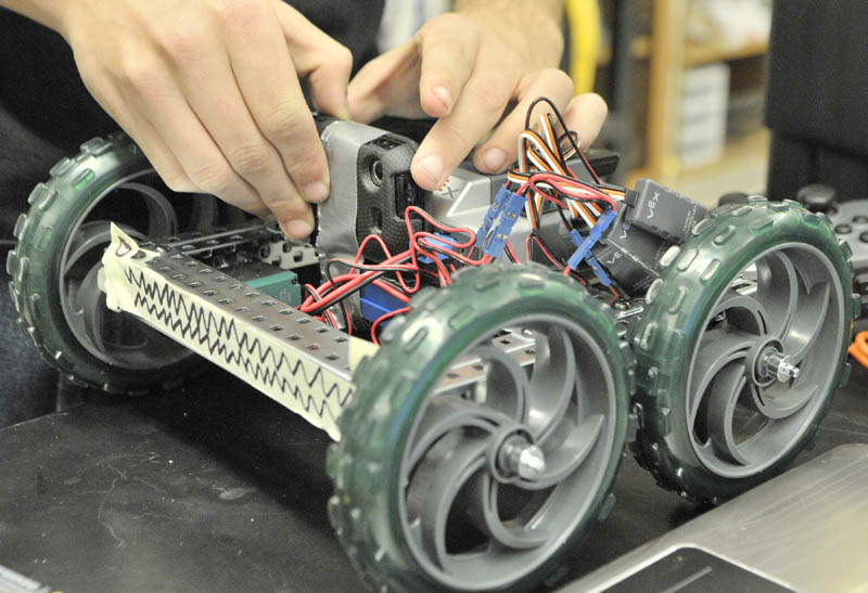 Cody Jackson tapes a cell phone onto a robot so that it could shoot a video of it running over the obstacle course on Thursday morning at Cony High School in Augusta.