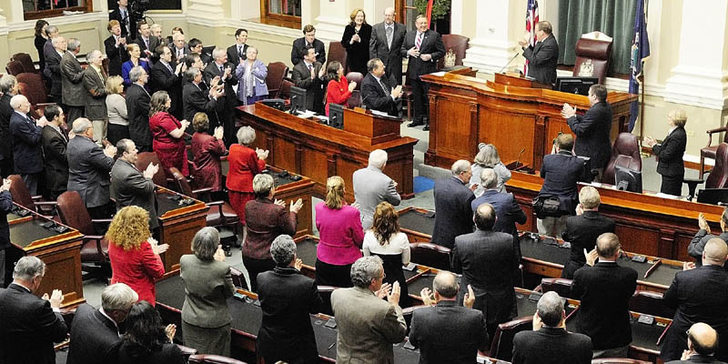 Gov. Paul LePage, third from left, back row, receives a standing ovation Tuesday night from Senate President Kevin Raye, at the podium, and legislators before giving his first State of the State address to a joint session of the Maine House and Senate at the State House in Augusta.