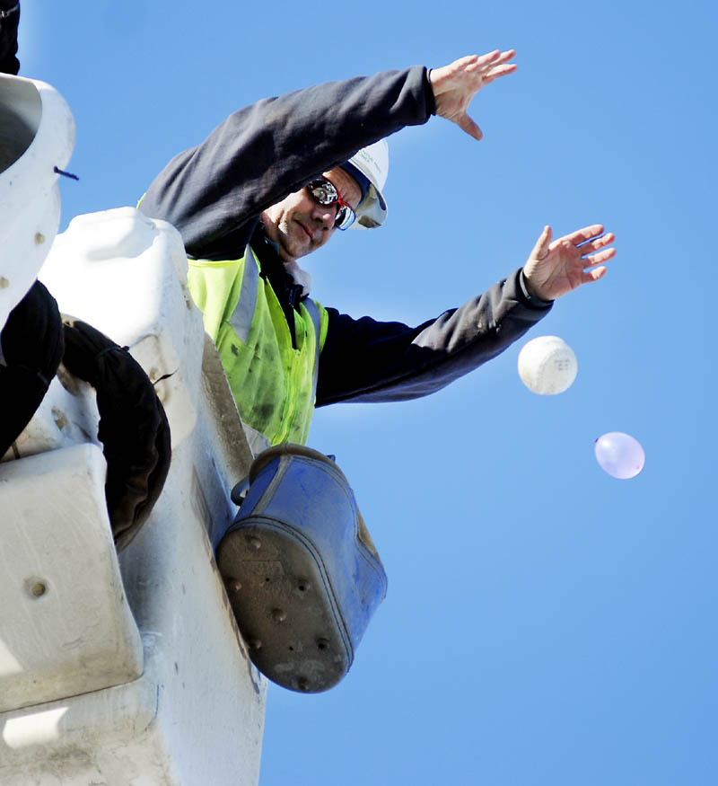 Central Maine Power lineman Carl Urquhart releases a ball and water filled balloon Monday at Maranacook Community Middle School in Readfield during a physics lesson for students on Newton's laws of motion. Urquhart and his partner, Ed Lake, dropped pumpkins, eggs and several balls from the bucket of their utility truck so the children could observe the items of different weight falling in tandem.