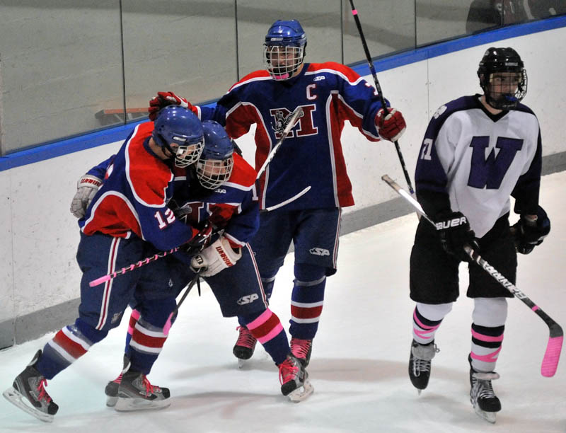 WORTH A CELEBRATION: Messalonskee High School teammates, from left to right, Chase Cunningham, James Varney and Sam Dexter celebrate after Cunningham scored a goal as Waterville Senior High School’s Chris Lee, right, skates by in the first period Tuesday at Alfond Rink at Colby College in Waterville.