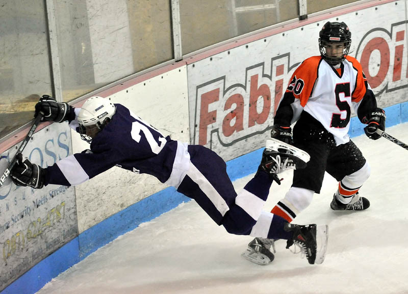 FINISH THE CHECK: Skowhegan Area High School’s Chase Whittemore, 20, right, checks Hampden Academy’s Kent Reichel into the boards during the first period Wednesday night at Sukee Arena in Winslow.