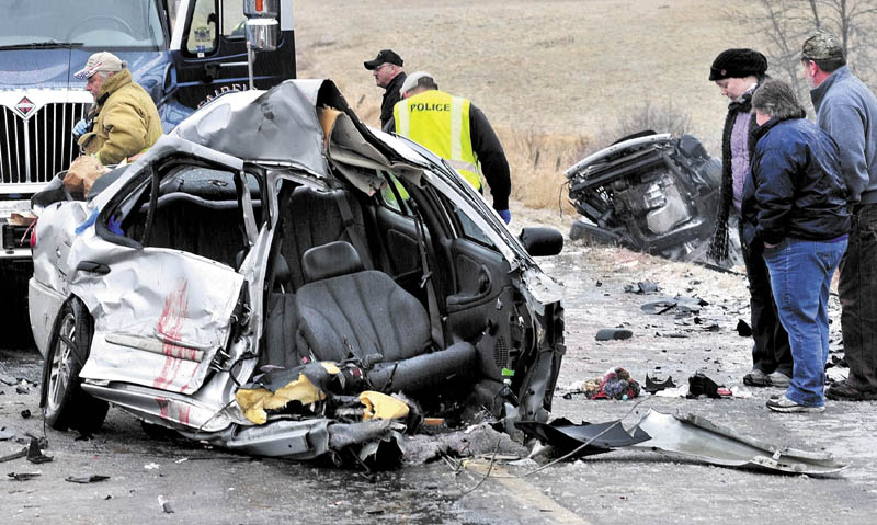 HORRIFIC ACCIDENT: Fairfield police officers and bystanders surround a vehicle that was split in half after colliding with another vehicle on U.S. Route 201 in Fairfeld late Saturday morning causing serious injuries to the driver and two others. The front half of the car is in the background.