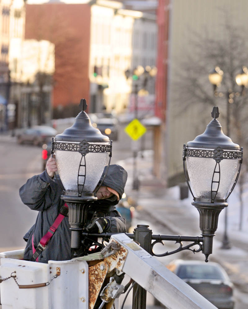 Ross Hutchings II, of Hutchings Electric, installs a street light on Wednesday after on Water Street in downtown Augusta. He was replacing one that was destroyed when a tractor-trailer rolled over after hitting the nearby railroad trestle last week.