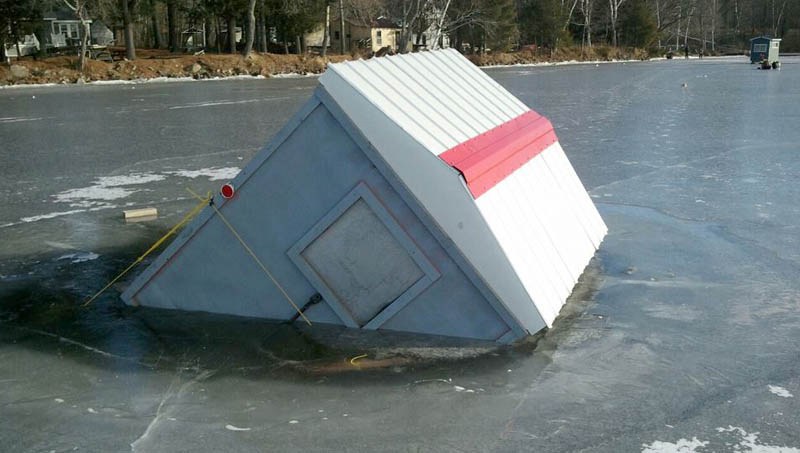 An fishing shack sits partially submerged Wednesday in the ice of Wesserunsett Lake in East Madison. Recent warm temperatures turned colder, encasing the shack.