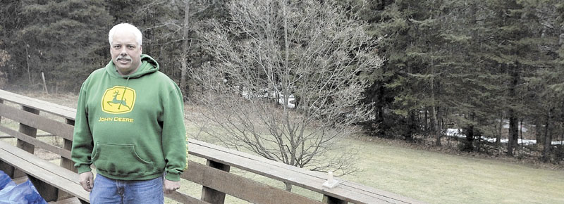 Rocky Gravel stands on the back deck of his Shorey Road residence in Winslow with a little brook in the back ground. According to FEMA, that brook put him in a flood plain. It cost him $2,000 to prove otherwise.