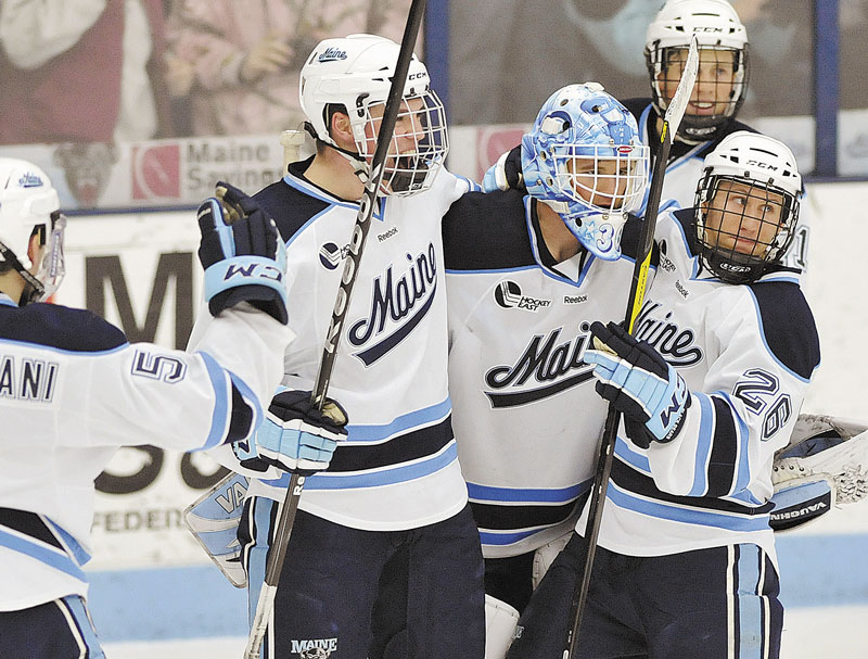 WE DID IT: Maine’s Andrew Cerretani, left, Jake Rutt, second from left, and Adam Shemansky, right, congratulate goalie Dan Sullivan, center, after defeating Boston College on Saturday in Orono.