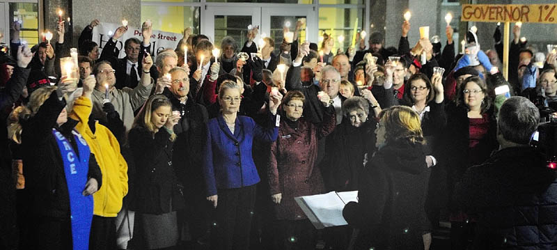 The Rev. Jill Saxby, executive director the Maine Council of Churches, center at podium, speaks during a candlelight vigil outside the State House before Gov. Paul LePage's first State of The State address on Tuesday night in Augusta.