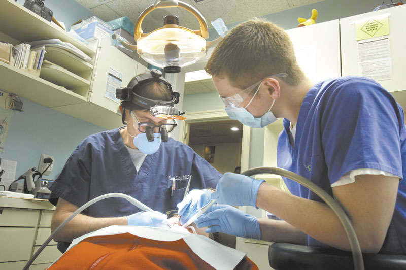 OPEN WIDE: Dr. Barry Saltz, left, assisted by Tim Kilgo, works with patient Danielle Romanoff in his Portland dentistry office on Monday.