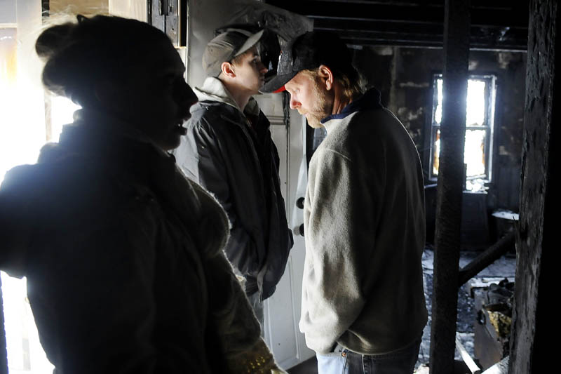 Siera Boucher, left, her neighbor, Scott Lucas, center, and her father, Kevin Boucher stand Monday in the burned entry way of the Boucher's home in Readfield. Boucher, 21, and her parents Kevin and Noreen Boucher, escaped their burning home Sunday night without injury. The home was gutted by fire.
