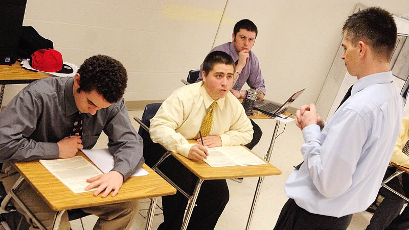 James Thurber, center, asks an intake interview question of business teacher Ryan Wheaton as they practice for a tax preparation clinic. Classmates Micah Adams, left, and Matt Landry look on.