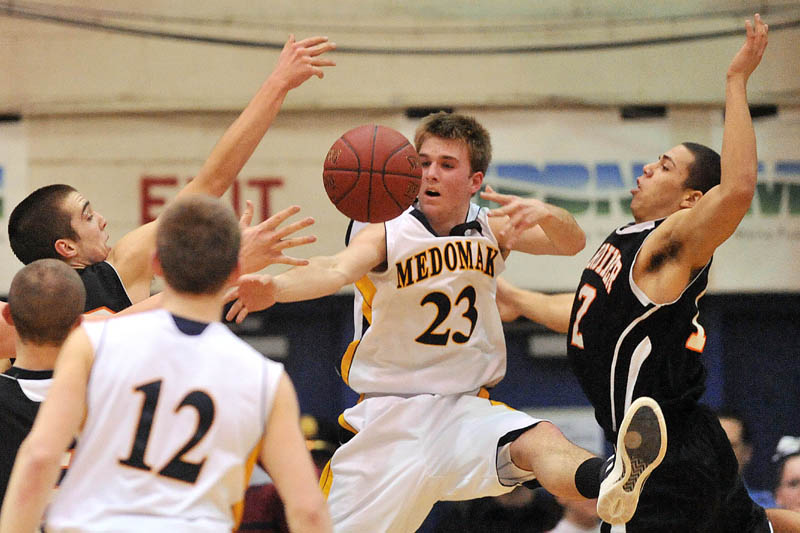 Photo by Michael G. Seamans Medomak Valley High School's Alex Greenrose, 23, tries to pass to teammate Shane Osier, 12, left, as Gardiner High School defenders Aaron Toman, 33, left, and Alonzo Connor, 12, right, try to steal the ball in the second half of the Eastern Class B semi-finals at the Bangor Auditorium Wednesday. Gardiner defeated Medomak Valley 57-46.