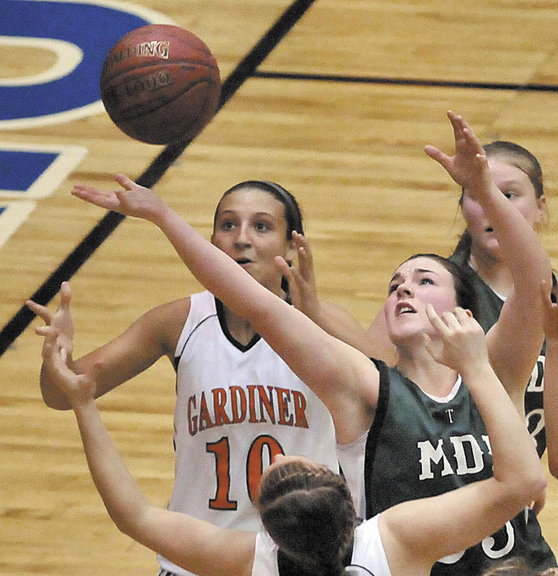 Photo by Michael G. Seamans Mount Desert Island High School's Hannah Shaw, 25, right, reaches for the ball as Gardiner High School's Katie McAllister, 10, left, looks for the rebound in the first half of the Eastern Class B quarterfinals game at the Bangor Auditorium Saturday. Gardiner defeated MDI 63-38.