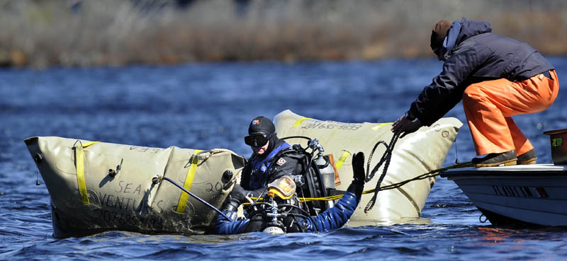 Ben Sniffen, right, hands diver Matt Sinclair a rope to harness an all terrain vehicle that he raised from Torsey Pond in Readfield with his father, Dave Sinclair, center, on Tuesday. The father and son diving team recover lost items below the surface together with Sniffen.