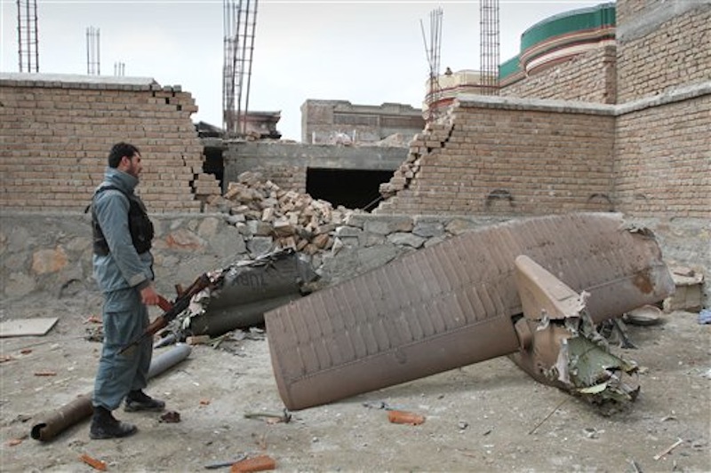 An Afghan policeman looks at the wreckage of a crashed Turkish helicopter on the outskirts of Kabul, Afghanistan on Friday, March 16, 2012. A Turkish military helicopter crashed into a house near the Afghan capital Friday, killing several Turkish soldiers on board and young girls on the ground, Turkish and Afghan officials said. (AP Photo/Musadeq Sadeq)
