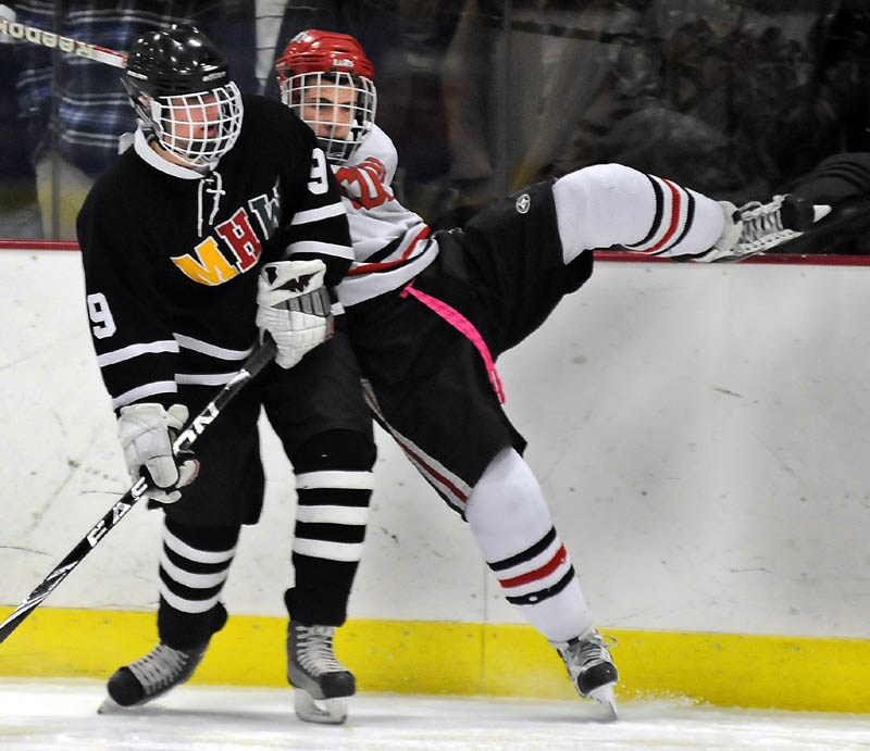 FACE OFF: Cony High School's Austin Davis, right, rides the boards while being checked by MHW's Jarred Hanson during a hockey match up Tuesday in Readfield.