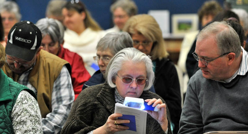 ANNUAL TRADITION: Cindy Taylor, center, and her husband Brad, right, read the annual report of the municipal officers during Albion's Town Meeting at the elementary school on Saturday.